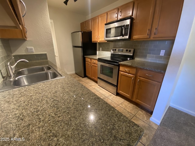 kitchen featuring backsplash, stainless steel appliances, a sink, and light tile patterned flooring