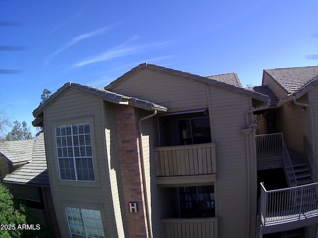 exterior space featuring a tile roof and brick siding