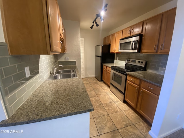 kitchen with light tile patterned floors, stainless steel appliances, a sink, and decorative backsplash