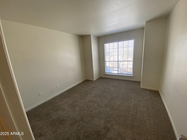 spare room featuring a textured ceiling, carpet flooring, and baseboards