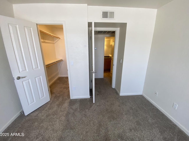 unfurnished bedroom with baseboards, visible vents, a spacious closet, carpet flooring, and a closet