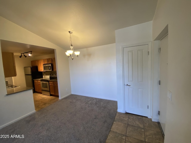 kitchen with carpet floors, brown cabinets, stainless steel appliances, dark countertops, and vaulted ceiling