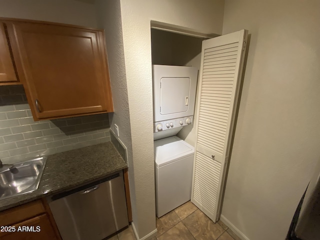 washroom featuring stacked washer / drying machine, laundry area, and a sink