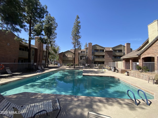 community pool featuring a residential view, a patio area, and fence