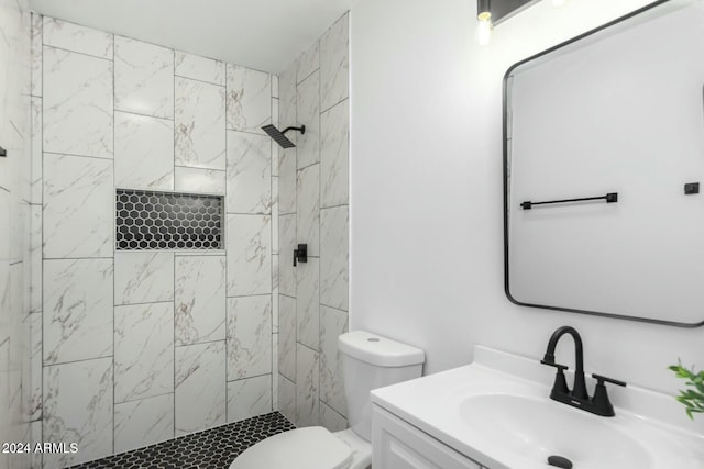 bathroom featuring toilet, vanity, and a tile shower