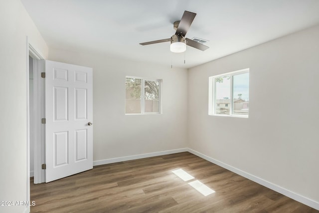 unfurnished room with ceiling fan, a healthy amount of sunlight, and wood-type flooring