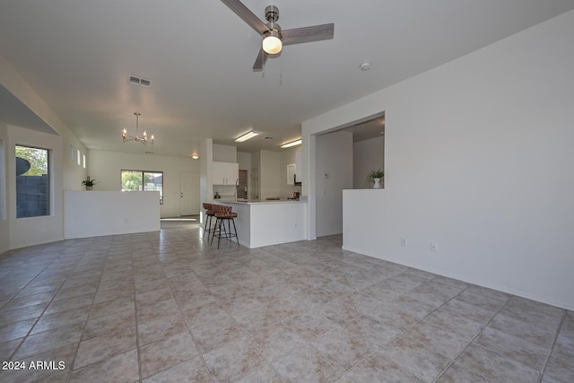 unfurnished living room featuring light tile patterned floors and ceiling fan with notable chandelier