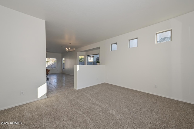 spare room featuring a chandelier, carpet floors, and plenty of natural light