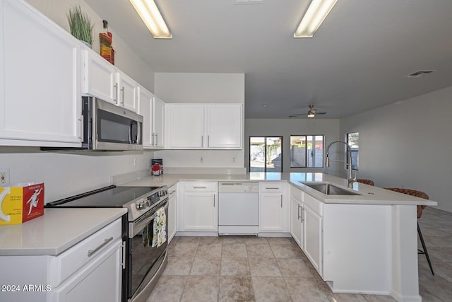 kitchen with kitchen peninsula, white cabinets, appliances with stainless steel finishes, and sink