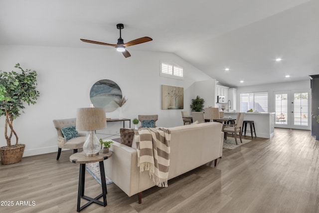 living room featuring baseboards, a ceiling fan, vaulted ceiling, light wood-style floors, and recessed lighting