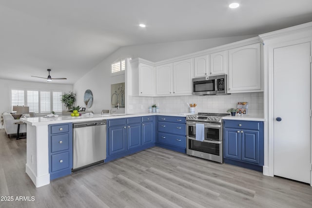 kitchen featuring blue cabinetry, stainless steel appliances, light countertops, white cabinetry, and a sink