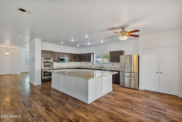 kitchen featuring dark hardwood / wood-style flooring, dark brown cabinetry, stainless steel appliances, ceiling fan, and a center island