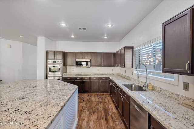 kitchen featuring dark hardwood / wood-style floors, light stone counters, sink, and appliances with stainless steel finishes