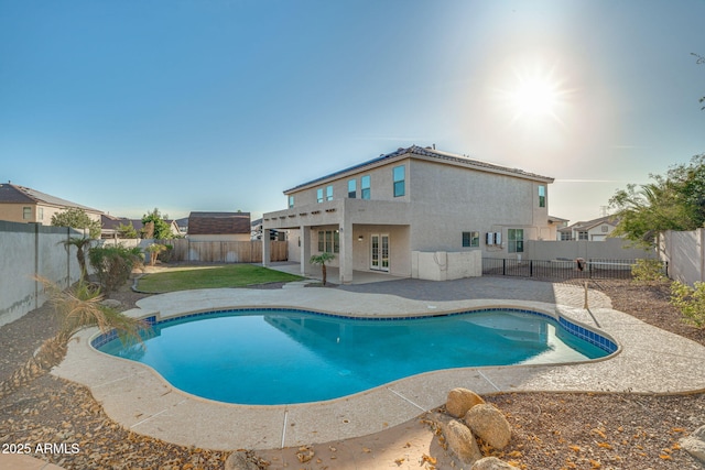 view of pool featuring french doors, a patio, and a lawn