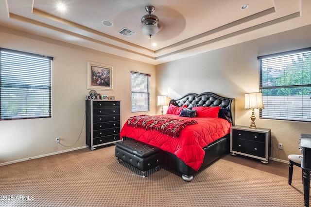 bedroom with a raised ceiling, carpet flooring, and ceiling fan