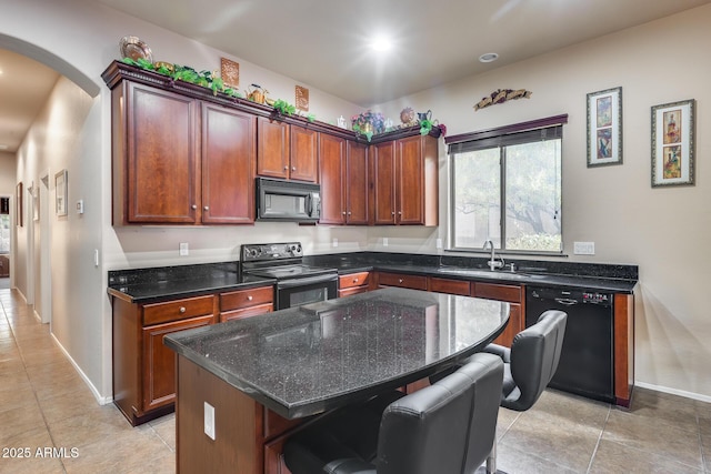 kitchen with sink, a center island, a kitchen breakfast bar, dark stone counters, and black appliances