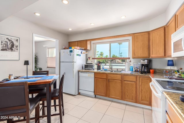 kitchen featuring light stone countertops, sink, light tile patterned floors, and white appliances