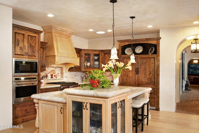 kitchen featuring a center island, light hardwood / wood-style floors, custom range hood, and appliances with stainless steel finishes