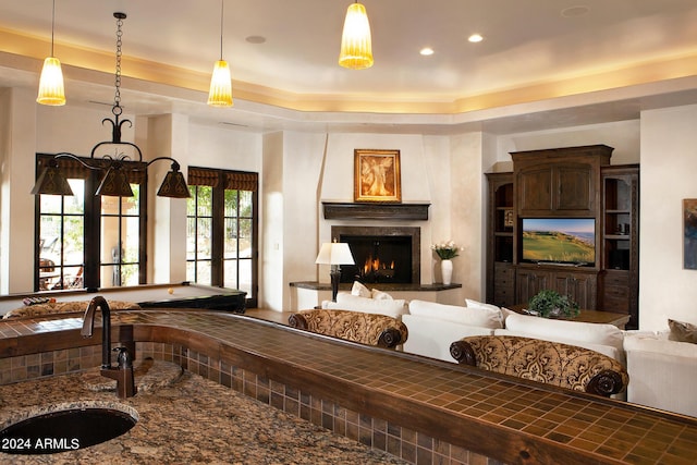 living room featuring french doors, a raised ceiling, plenty of natural light, and sink