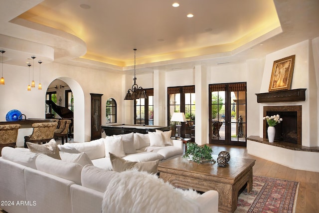 living room with hardwood / wood-style floors, a tray ceiling, and french doors