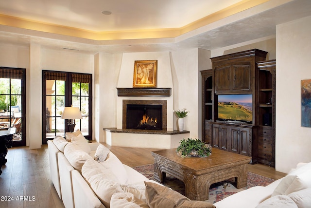 living room with light hardwood / wood-style floors, a raised ceiling, and french doors