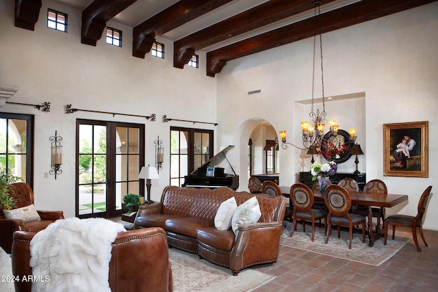 living room with french doors, a towering ceiling, an inviting chandelier, and beam ceiling