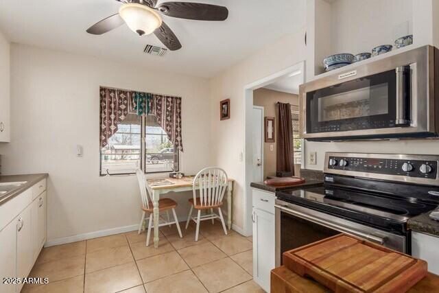 kitchen featuring stainless steel appliances, light tile patterned floors, white cabinetry, visible vents, and a ceiling fan