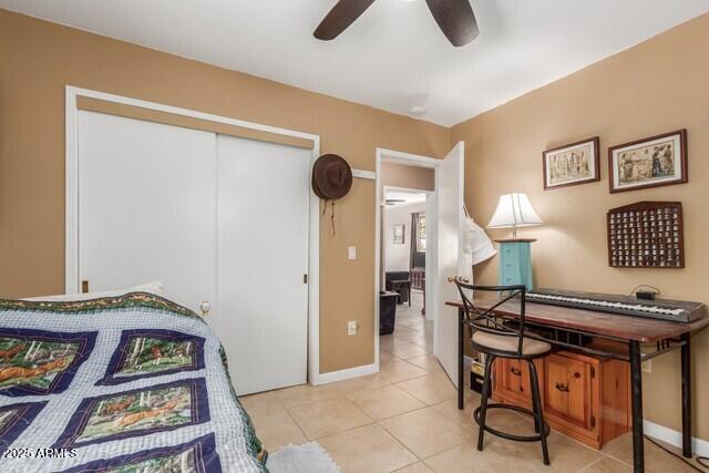 bedroom with a closet, ceiling fan, tile patterned floors, and baseboards