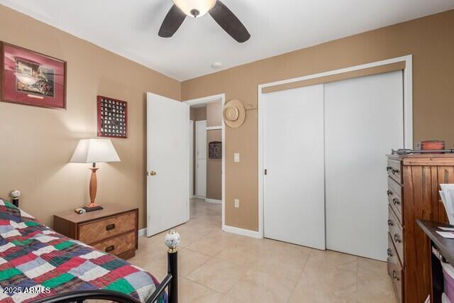 bedroom with baseboards, a ceiling fan, light tile patterned flooring, and a closet