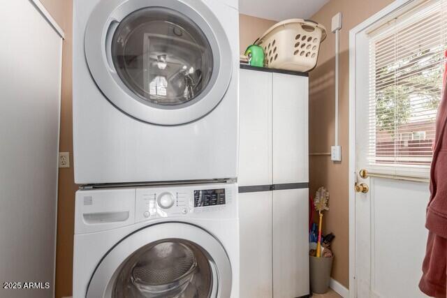 clothes washing area with stacked washer and dryer and cabinet space