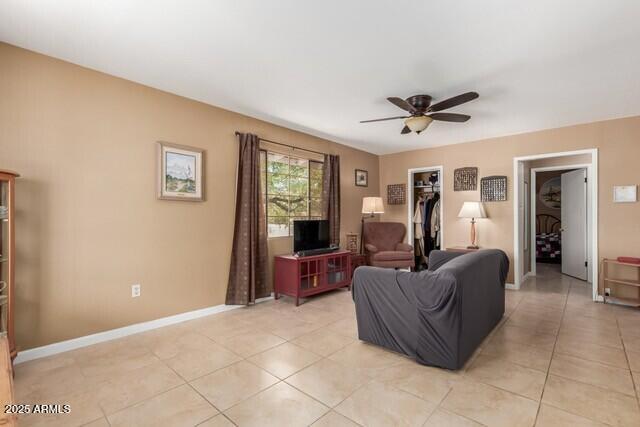 living room with baseboards, a ceiling fan, and light tile patterned flooring