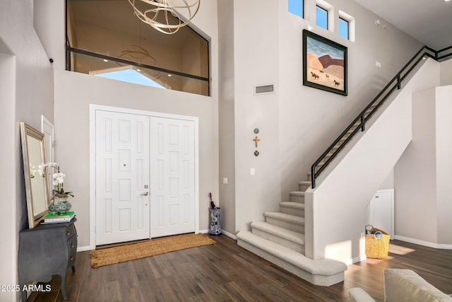 entryway featuring a notable chandelier, a towering ceiling, dark hardwood / wood-style floors, and a healthy amount of sunlight