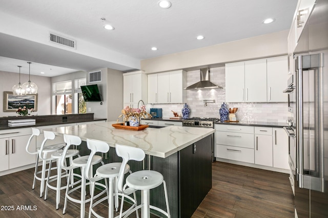 kitchen featuring white cabinetry, wall chimney exhaust hood, and a center island