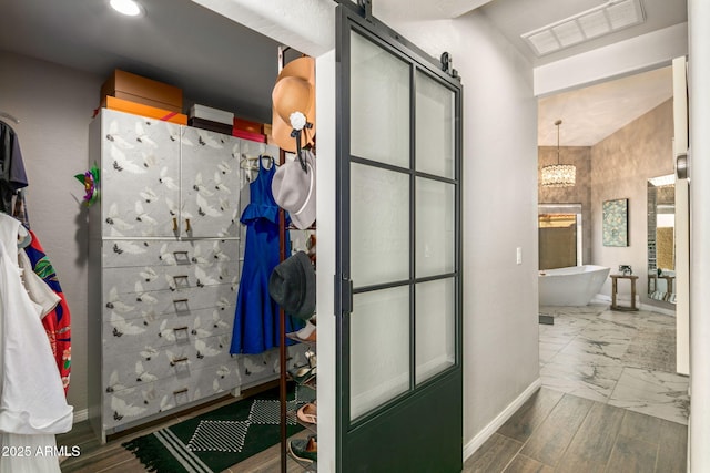 bathroom with a chandelier, a bathtub, and hardwood / wood-style floors