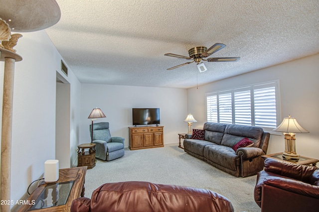 living room with a textured ceiling, ceiling fan, visible vents, and carpet