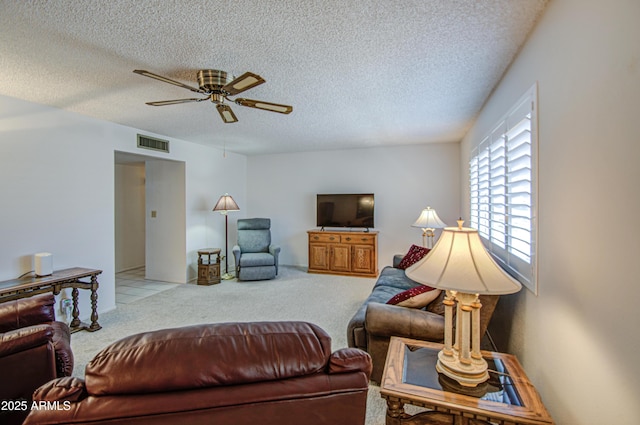 living area with a textured ceiling, visible vents, a ceiling fan, and light carpet