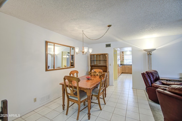 dining space featuring light tile patterned flooring, a textured ceiling, a chandelier, and visible vents