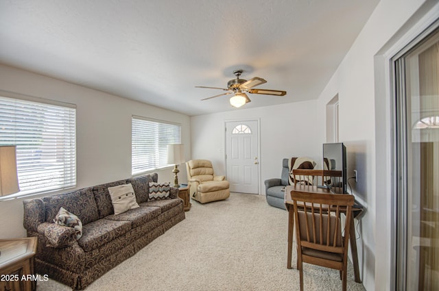 carpeted living area with a ceiling fan