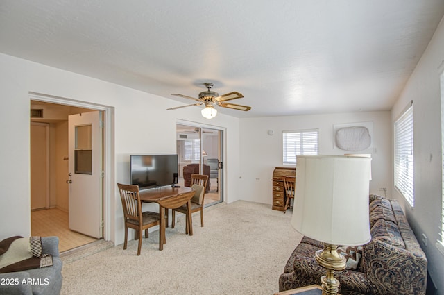 living room with visible vents, light carpet, and ceiling fan