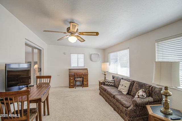 carpeted living area with ceiling fan