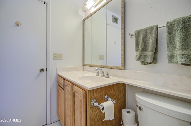 bathroom featuring toilet, vanity, and visible vents