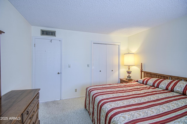 carpeted bedroom featuring a closet, a textured ceiling, and visible vents