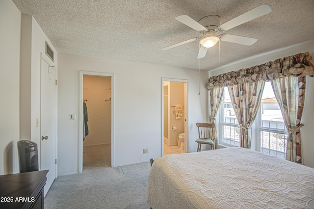 bedroom with a textured ceiling, connected bathroom, and carpet