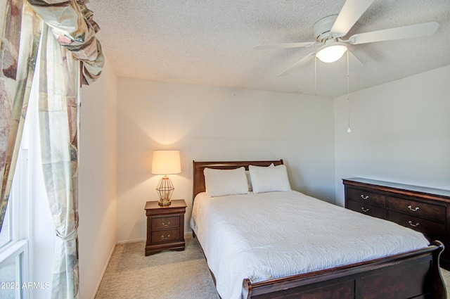 bedroom featuring baseboards, a textured ceiling, a ceiling fan, and light colored carpet