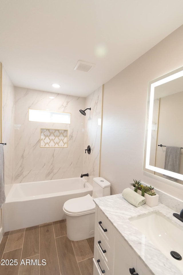 full bathroom featuring tiled shower / bath, vanity, and toilet