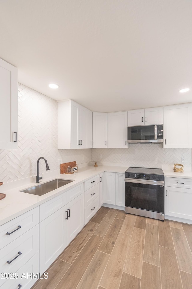 kitchen with range with electric cooktop, sink, white cabinets, and decorative backsplash