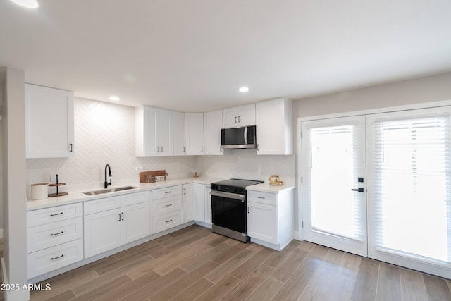 kitchen featuring sink, decorative backsplash, white cabinets, and appliances with stainless steel finishes