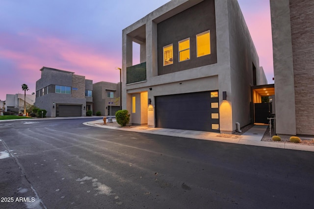 contemporary house with stucco siding, driveway, and an attached garage