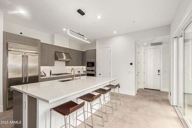 kitchen featuring modern cabinets, a sink, a kitchen breakfast bar, built in appliances, and extractor fan