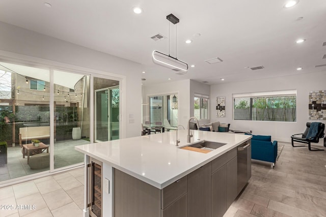 kitchen featuring visible vents, a sink, open floor plan, stainless steel dishwasher, and a kitchen island with sink